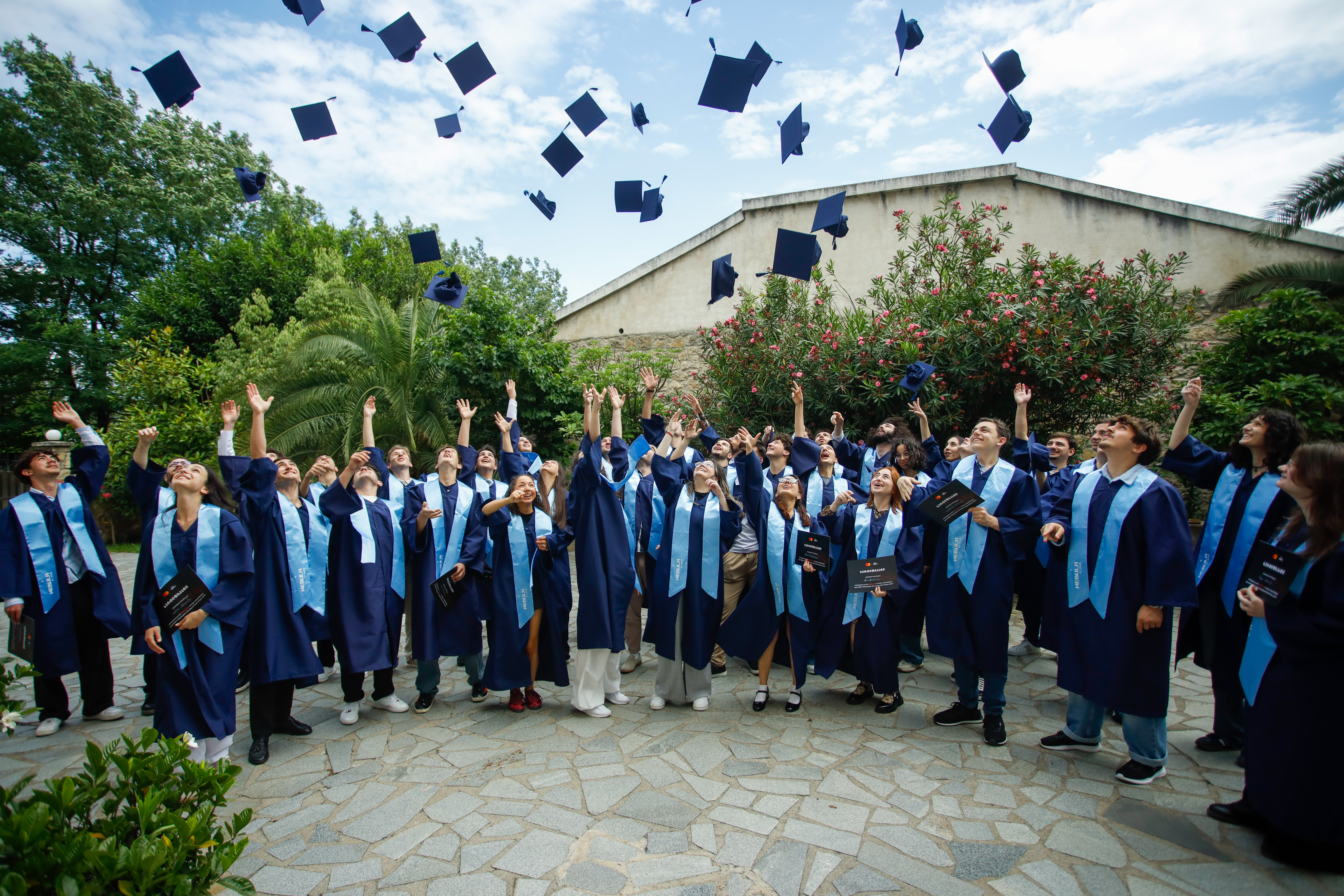 Graduates celebrating at Nebula AI Hub commencement, tossing caps